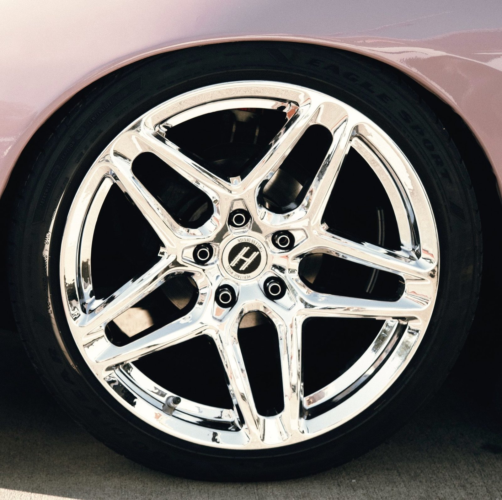A bright chrome alloy wheel on a parked car.