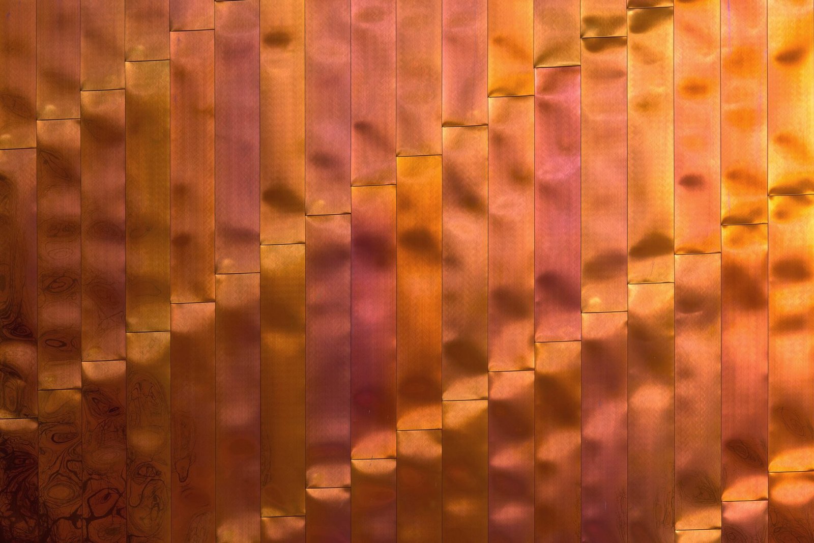 Overlapping copper panels in warm orange and rose tones.