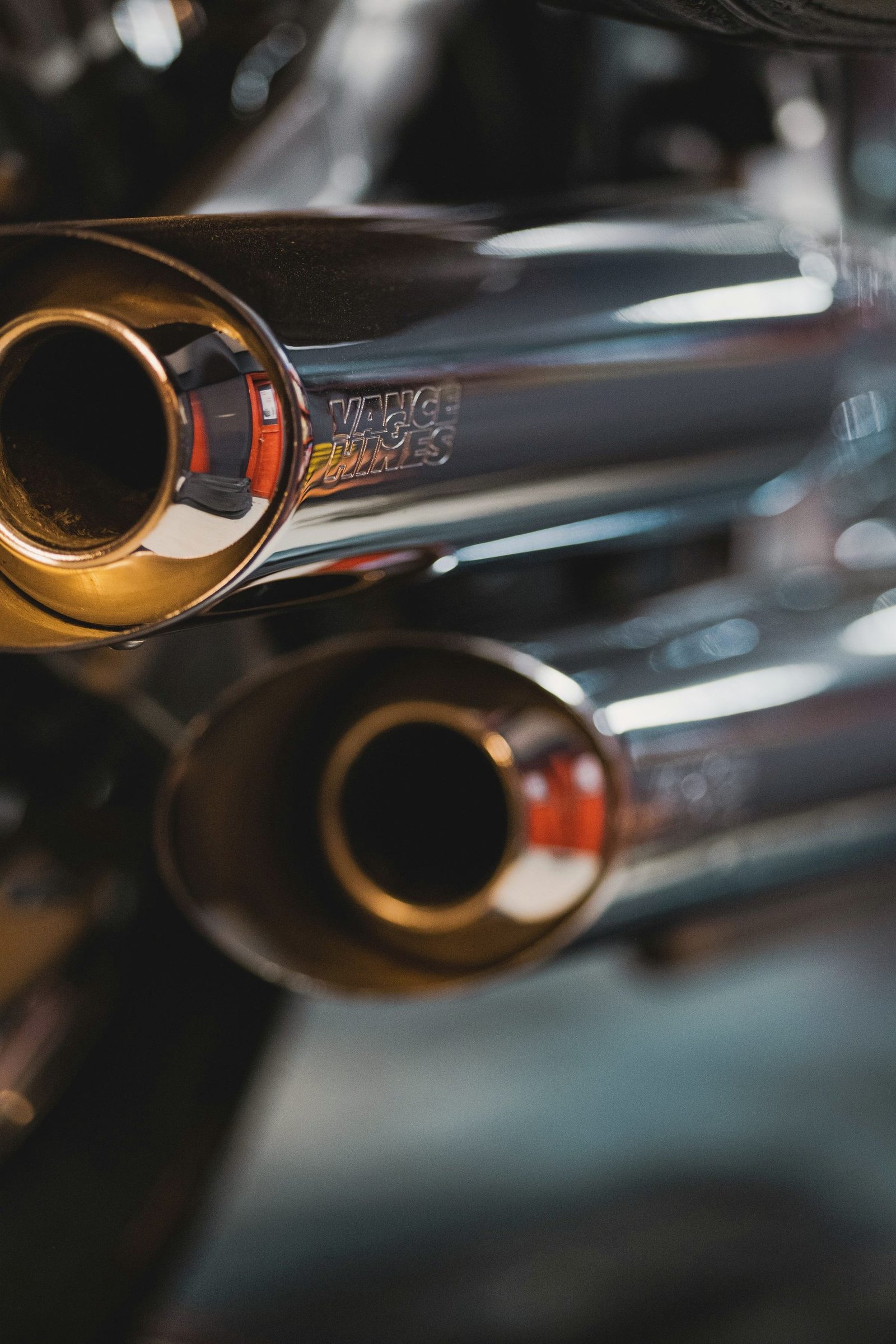 Polished motorcycle exhaust tips catching warm light.